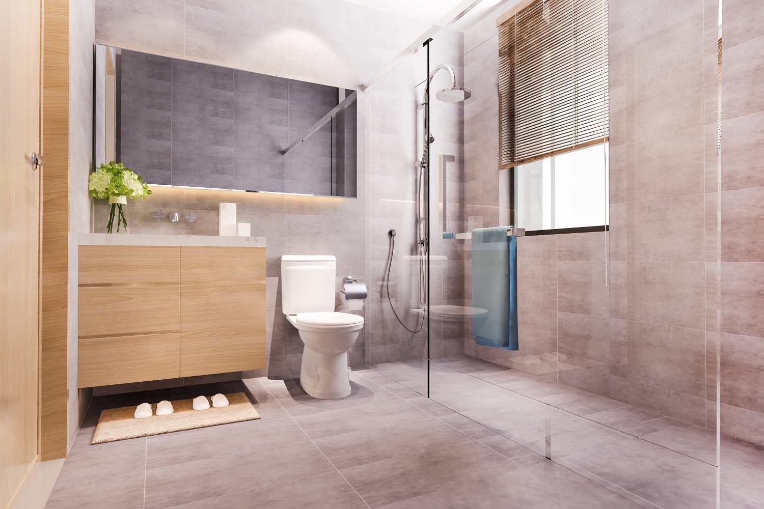Modern bathroom with beige tiles, a wooden vanity, mirror, toilet, and glass shower. A blue towel hangs by the shower. A plant decorates the sink area. Natural light from a window.